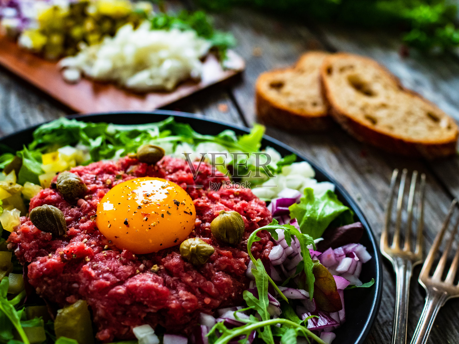 鞑靼牛肉配洋葱、酸豆和腌黄瓜放在木桌上照片摄影图片