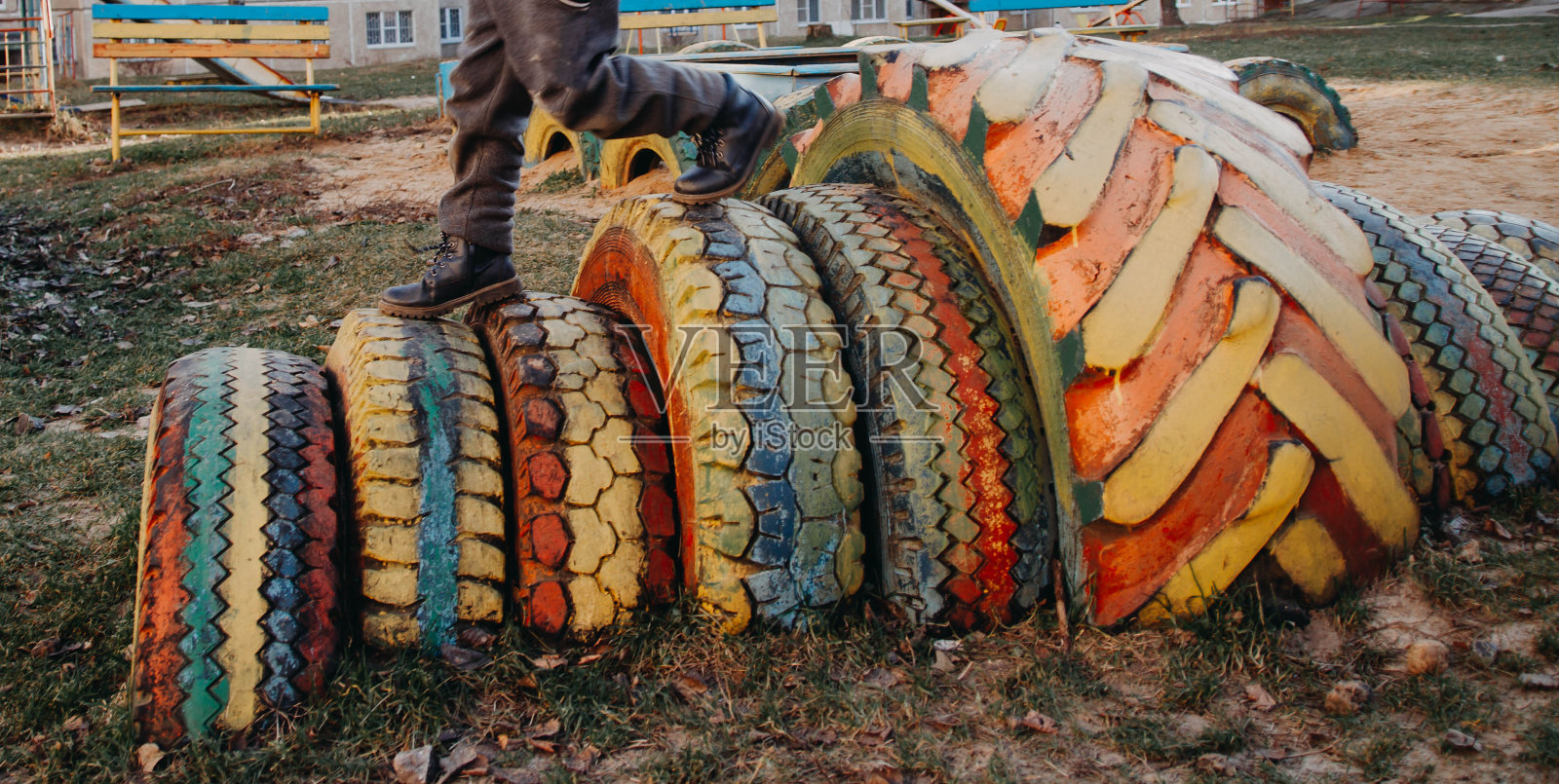 游乐场是用旧汽车轮胎做的。轮胎,用彩色颜料涂的轮胎。孩子用挖在地上的轮胎跑。有趣的游戏照片摄影图片