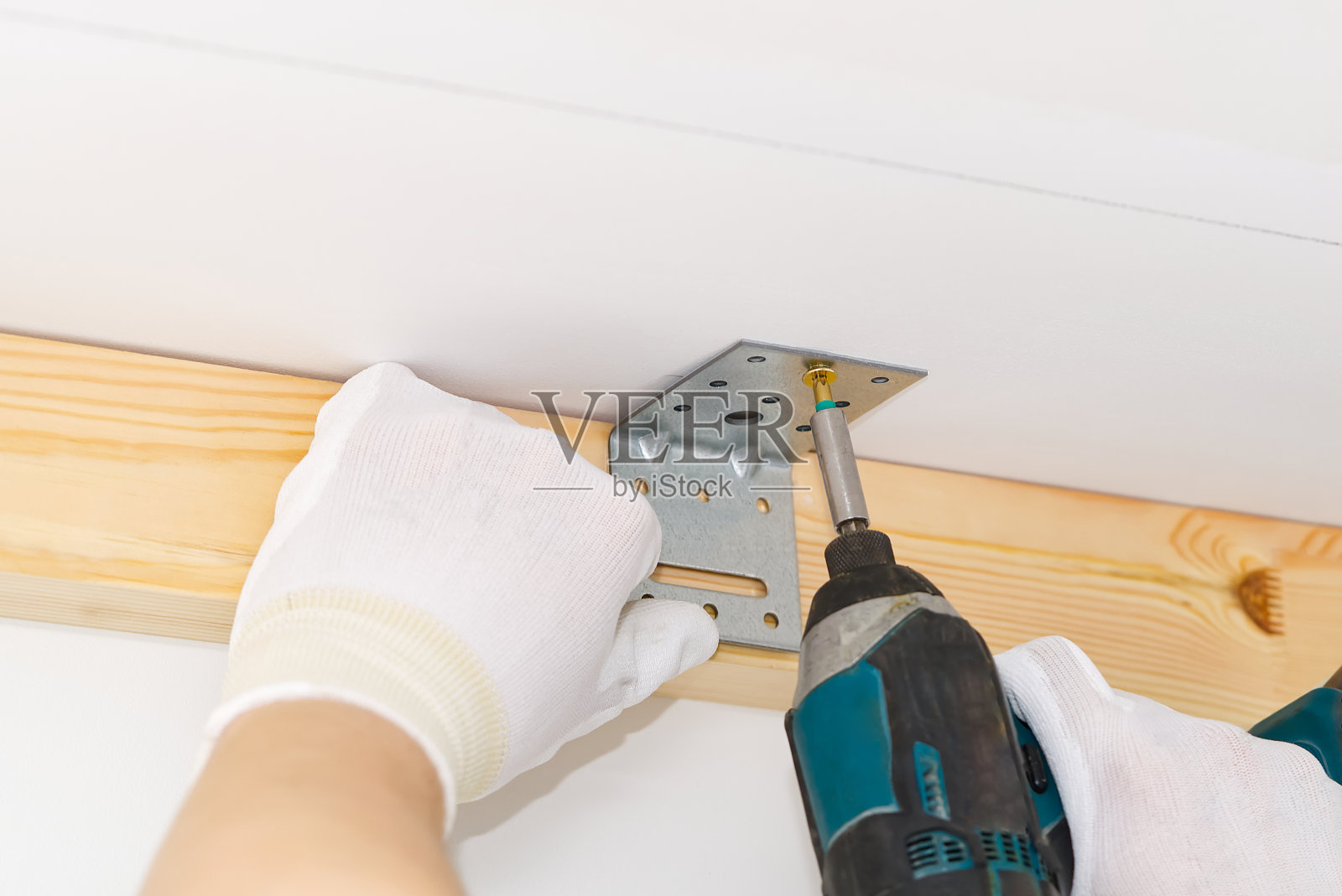 师傅用螺丝刀把金属角固定在混凝土天花板上,杂工照片摄影图片