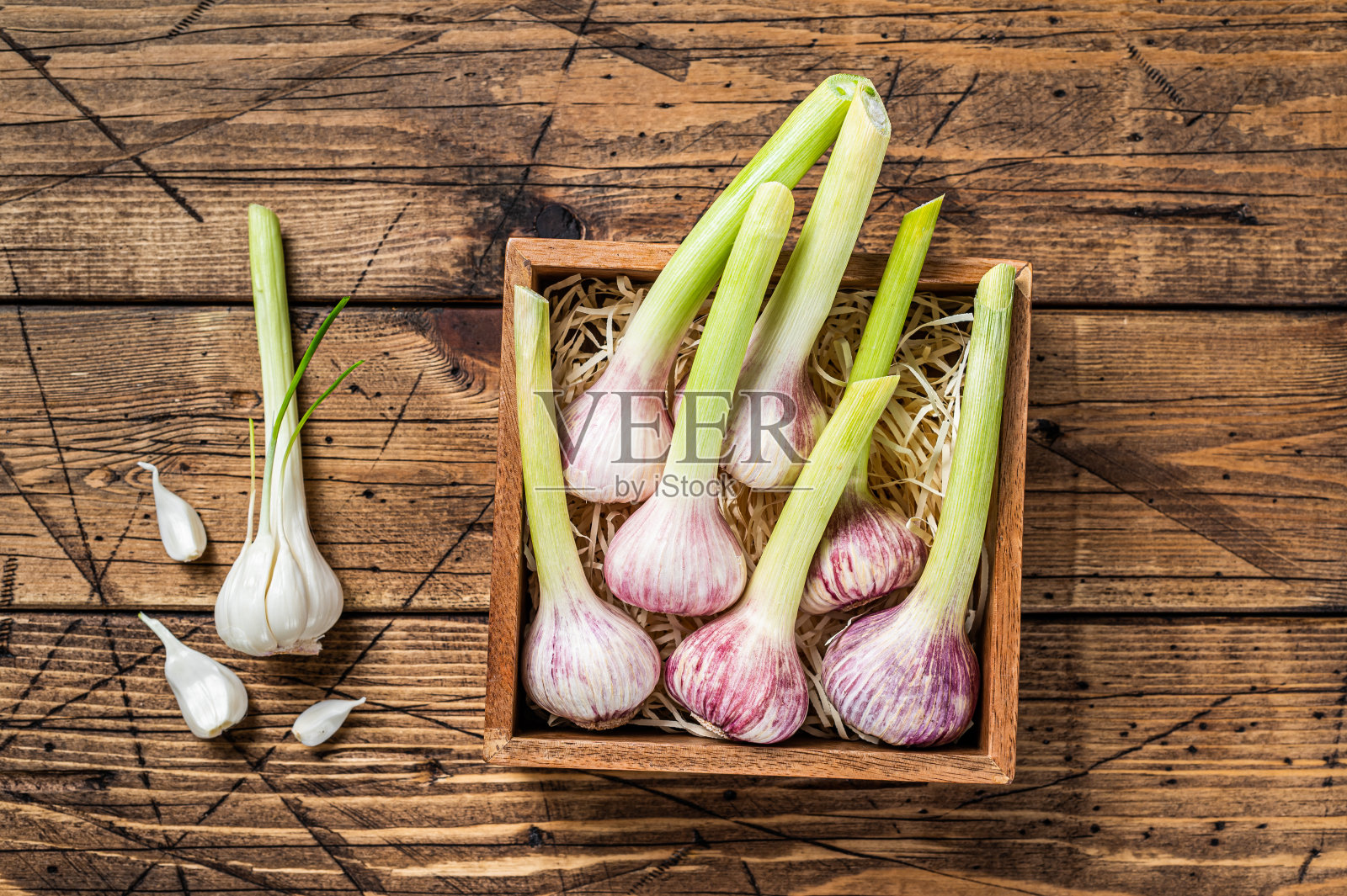 春天的蒜苗和蒜瓣放在木盒子里。木制背景。俯视图照片摄影图片