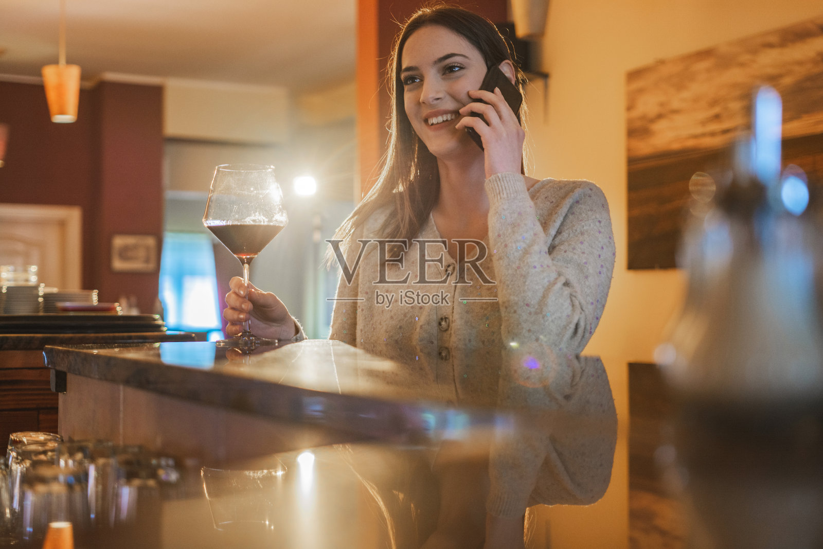 一个在酒吧里一边笑一边打电话的快乐女人照片摄影图片