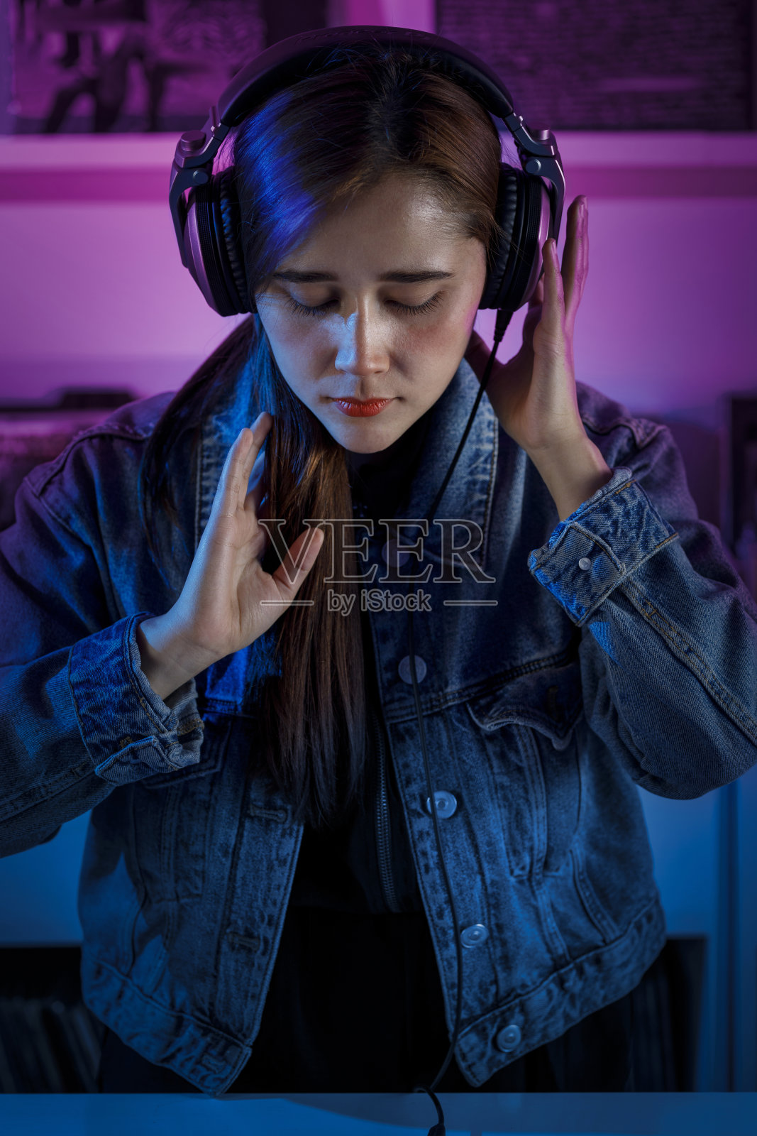 肖像可爱的年轻微笑的dj戴着耳机,在一个黑胶唱片店。复古的音乐概念照片摄影图片