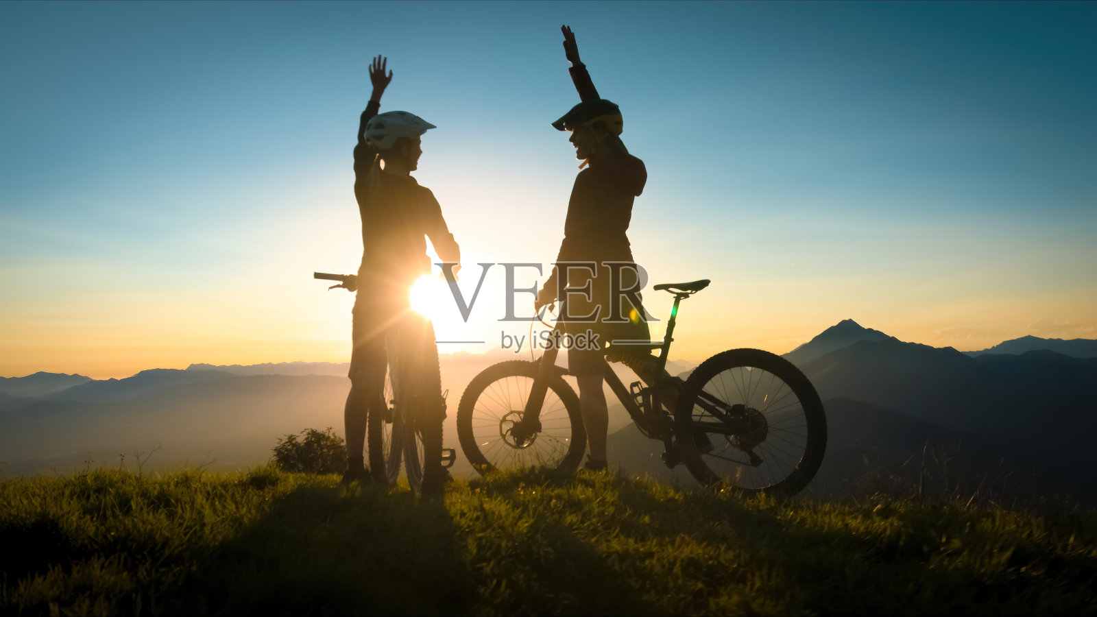 女人在山地车旅行日落击掌照片摄影图片