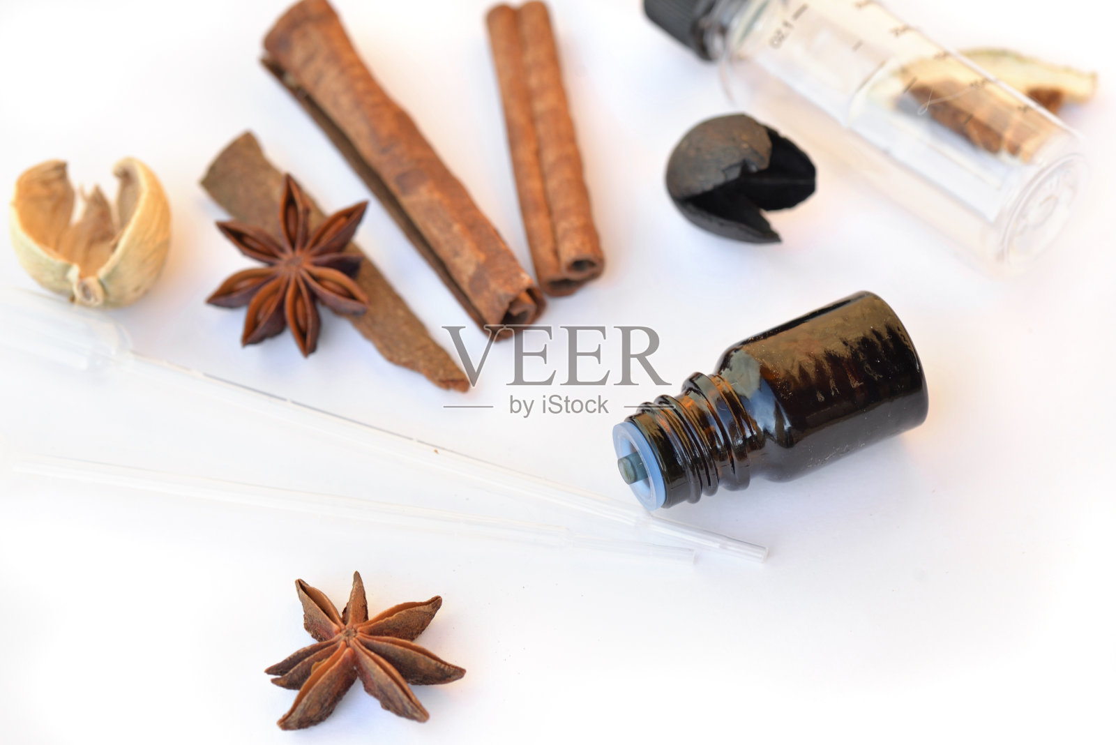 瓶精油,肉桂和茴芹在白色的背景下与吸管提取精华照片摄影图片