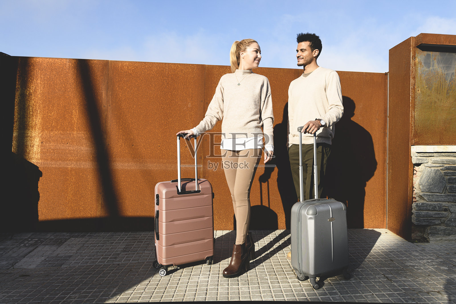 一对夫妇拿着行李站在街上。公路旅行照片摄影图片