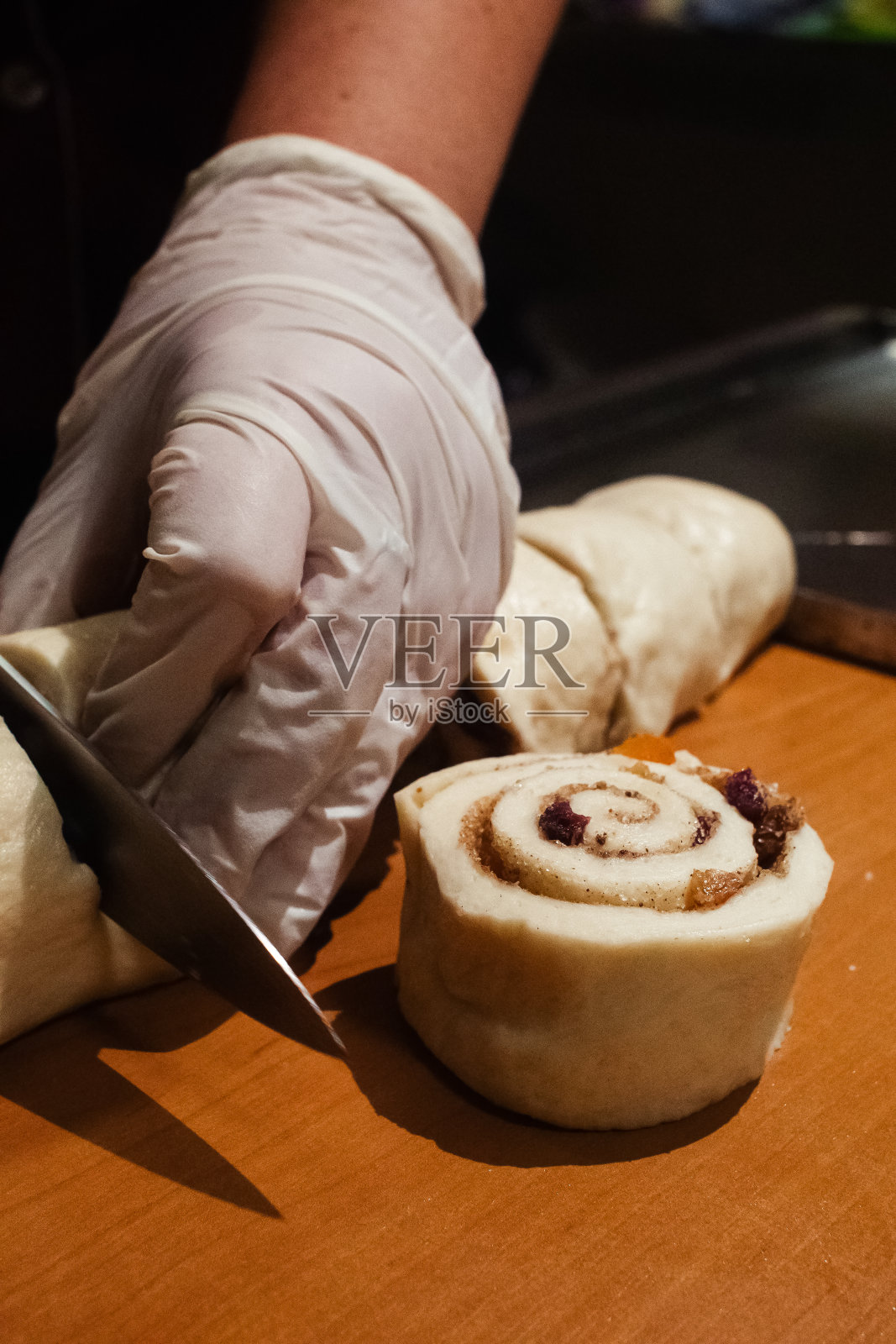 糕点师将蜜饯、葡萄干和巧克力块涂在松饼上。使面团卷。糕点师的工作。做甜点照片摄影图片