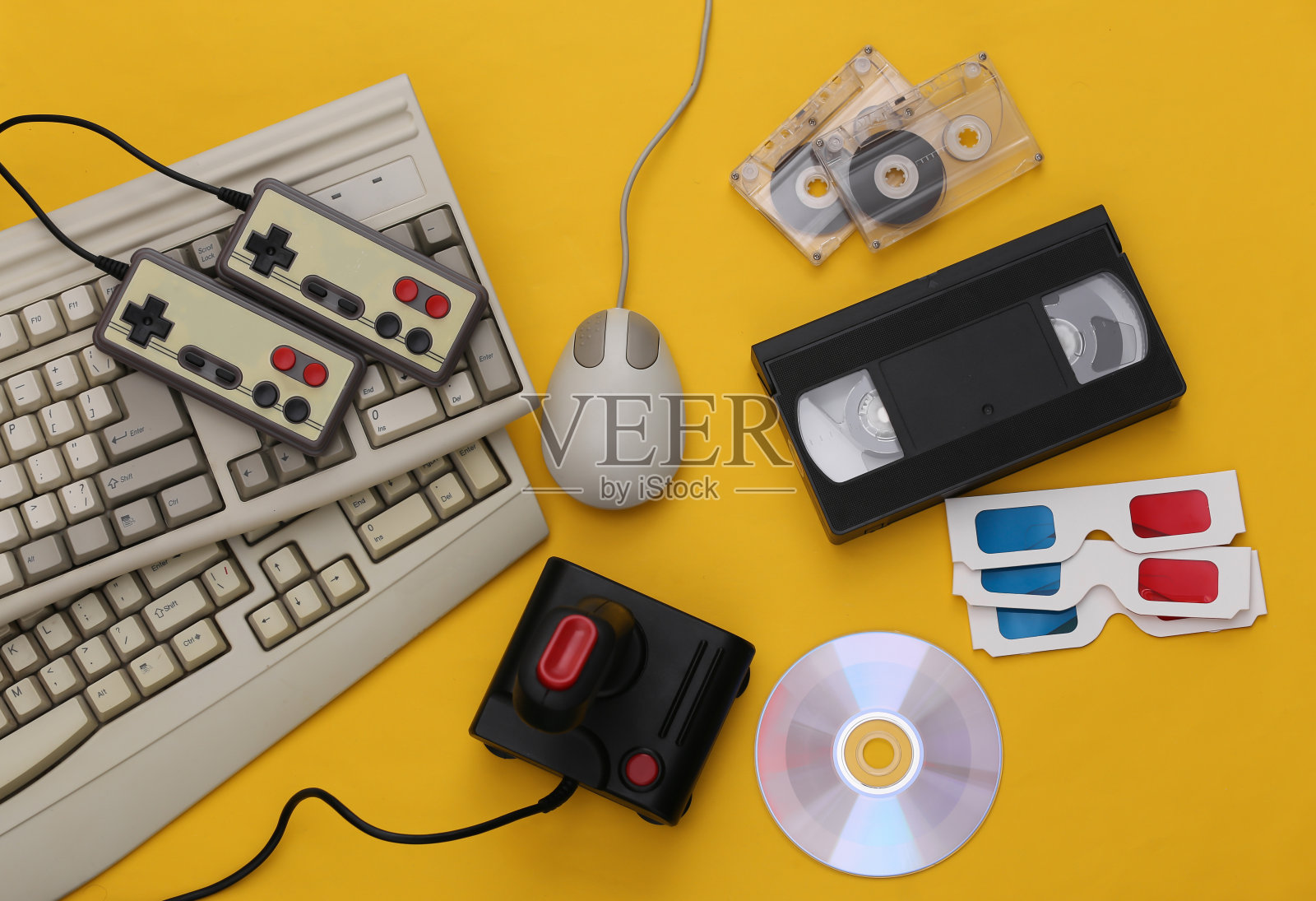 平铺80属性组成。PC键盘,鼠标,游戏手柄,音视频磁带,CD, 3D眼镜。复古电子产品,小玩意和设备。娱乐和游戏。黄色背景。俯视图照片摄影图片