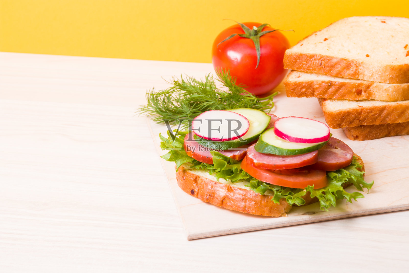 一个三明治蔬菜和减肥香肠放在桌子上,黄色的背景,面包和蔬菜的背景,健康早餐的概念照片摄影图片