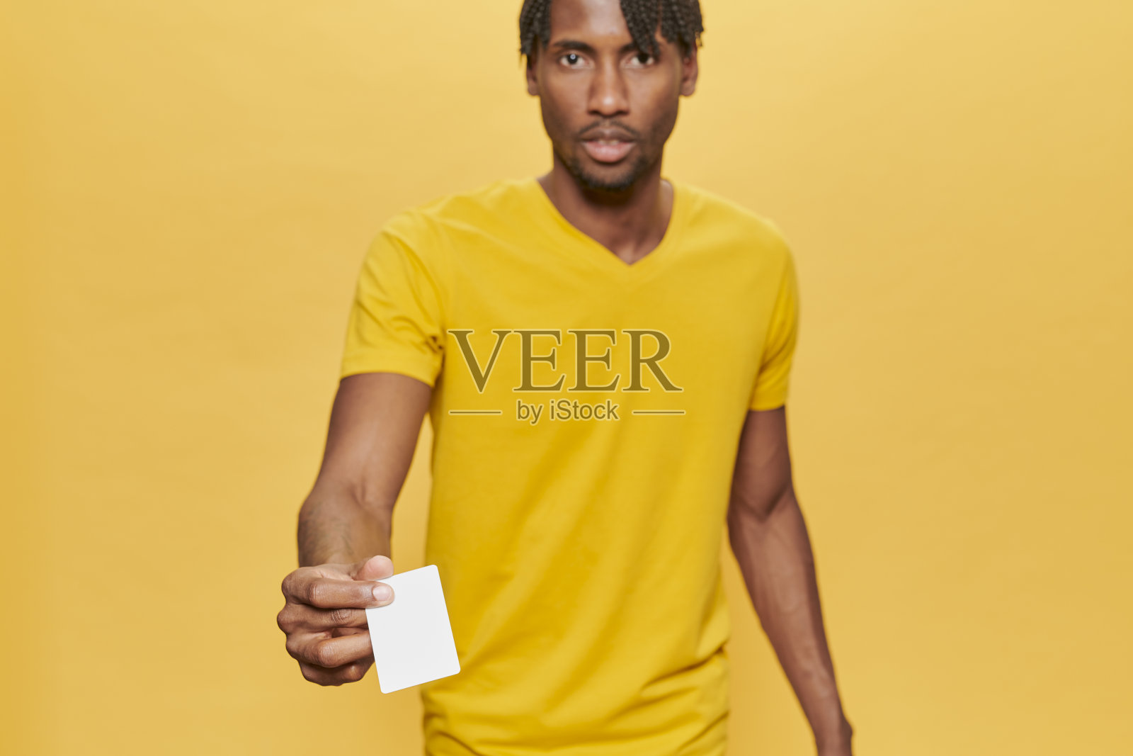 英俊的非洲男子在黄色背景穿着黄色t恤保持模拟信用卡照片摄影图片
