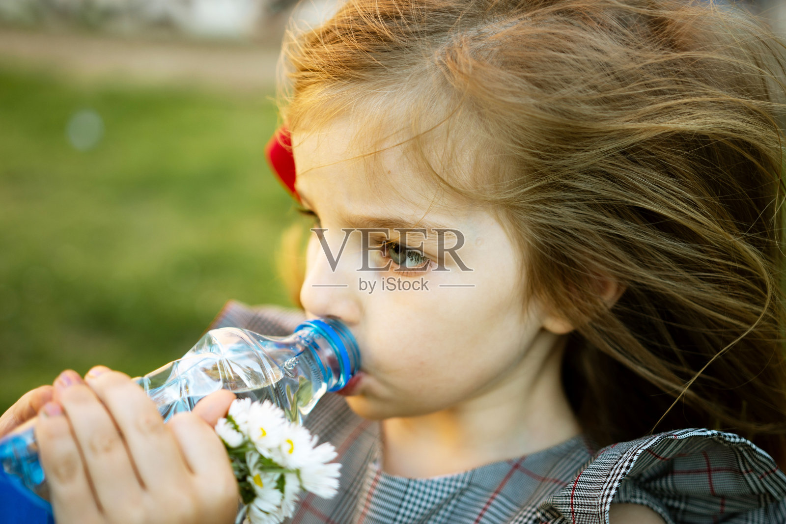 美丽的小女孩正在喝瓶子里的干净水。炎热的夏天照片摄影图片