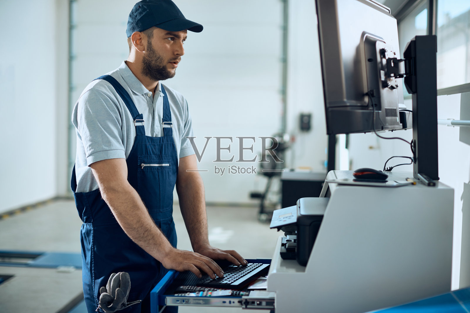 汽车修理工在汽车修理厂的台式机上工作。照片摄影图片