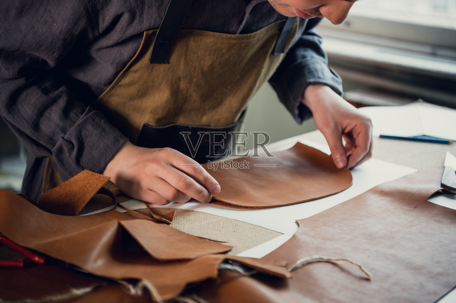 一个有才华的年轻人帮助他的父亲打理家族生意,用皮革剪出制鞋的空白照片摄影图片