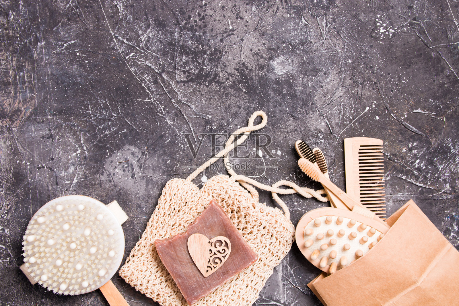 干脂肪团按摩刷,针织棉海绵,天然可可皂和一个带竹牙刷的纸袋,一个木制梳子和一个身体按摩器的黑色背景照片摄影图片