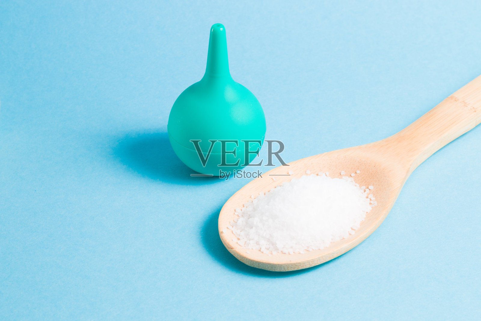 给鼻子灌肠,在浅蓝色的背景上用木勺加海盐,复制空间,用盐水用吸引器冲洗鼻子照片摄影图片