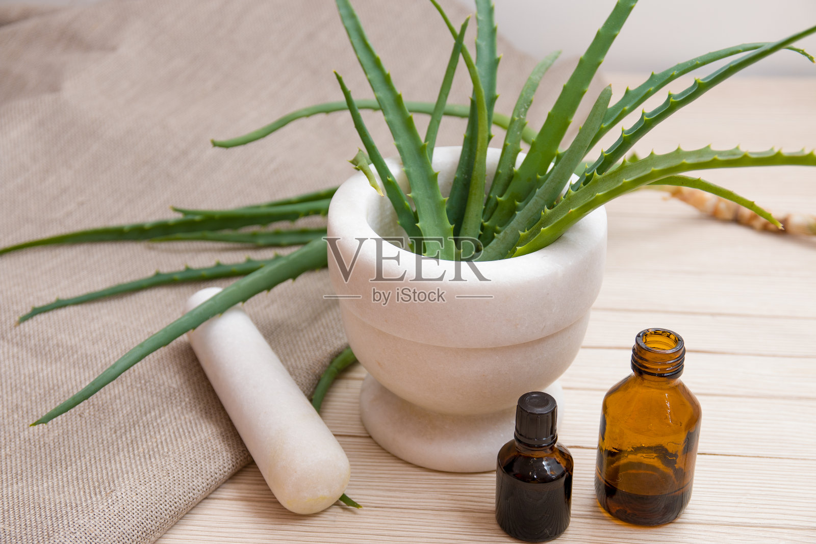 天然药物,芦荟在白色的石头砂浆,木制的木板表,米色背景,亚麻织物,黑色玻璃小瓶,治疗疾病照片摄影图片
