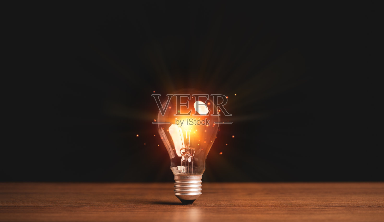 木制桌子上的灯泡发出橙色的光,有创意的想法和创新的概念。照片摄影图片