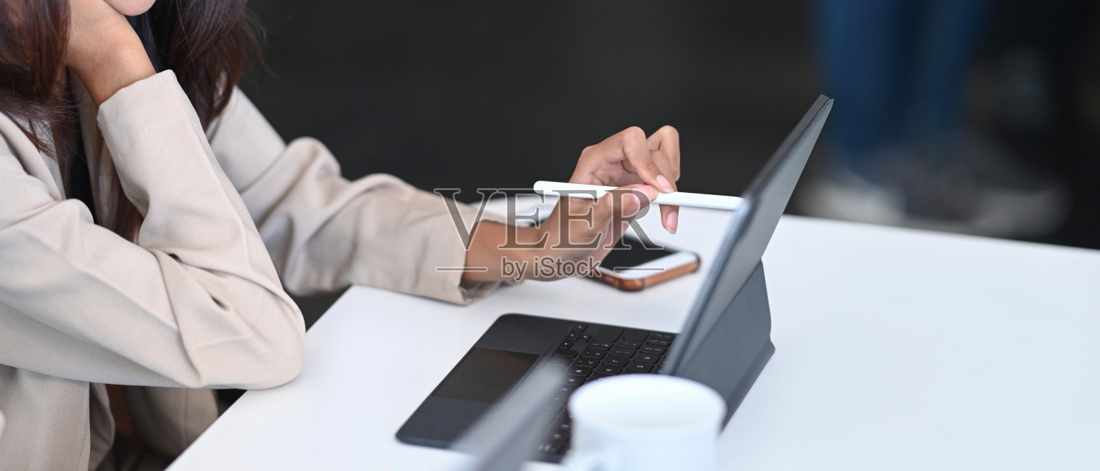 短镜头女商人拿着手写笔指着她的办公桌上的数字平板电脑。照片摄影图片