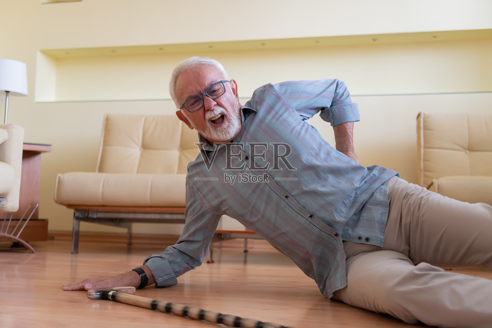 一位拄着拐杖的老人在发生事故后躺在地板上。照片摄影图片