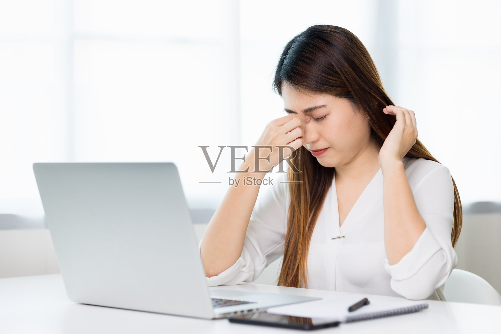年轻的亚洲商务女性揉她的眼睛,她感到抑郁,压力,头痛,由于长时间使用笔记本电脑而感到疲劳,她出现了办公室综合症。照片摄影图片