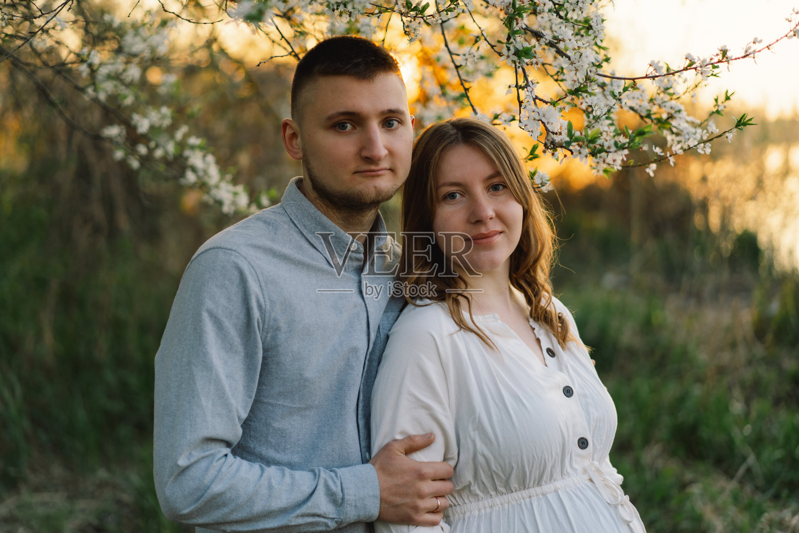 年轻美丽的夫妇拥抱在春天的花园。照片摄影图片