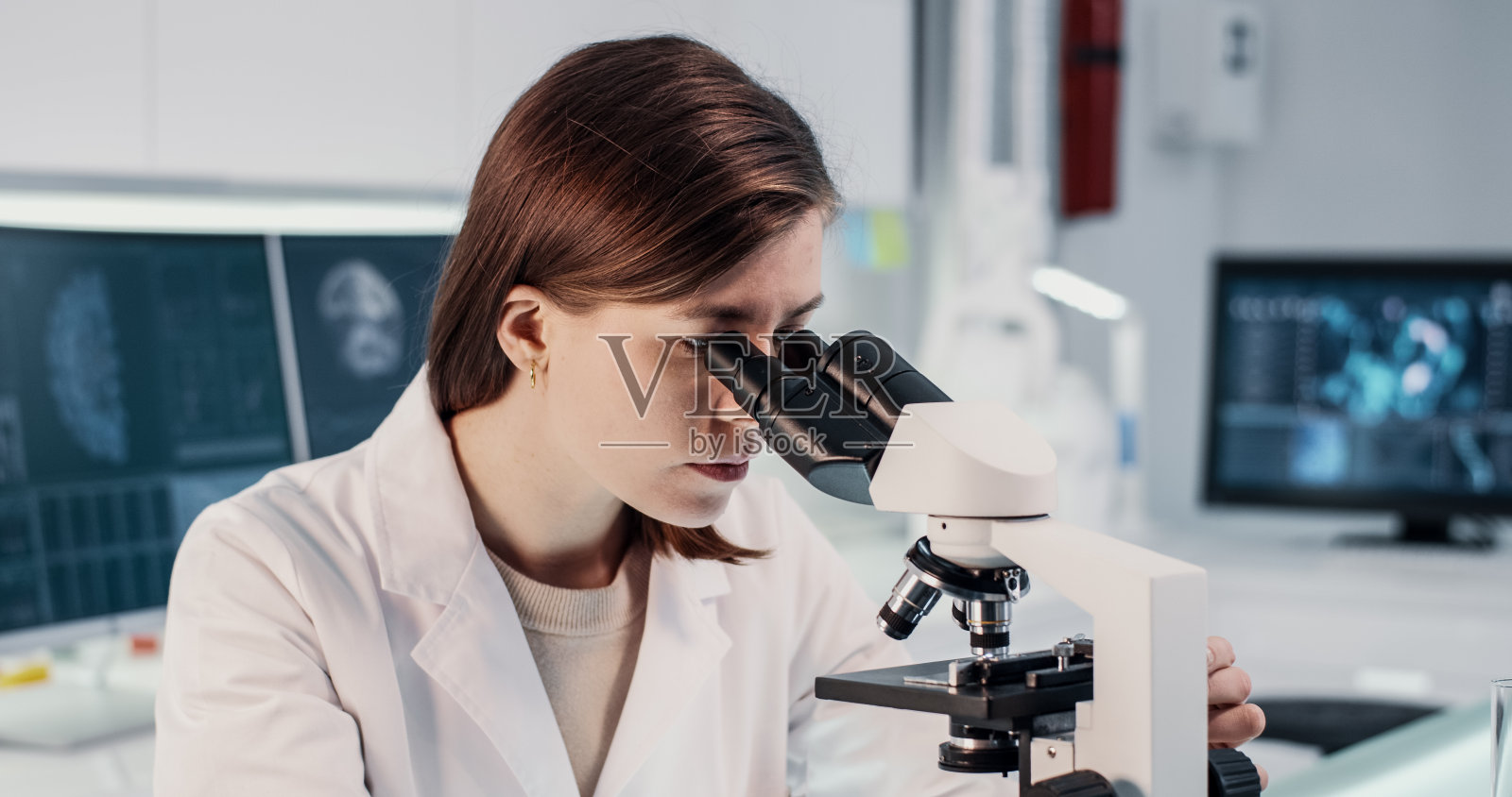研究病原体样本的女医生。使用显微镜照片摄影图片