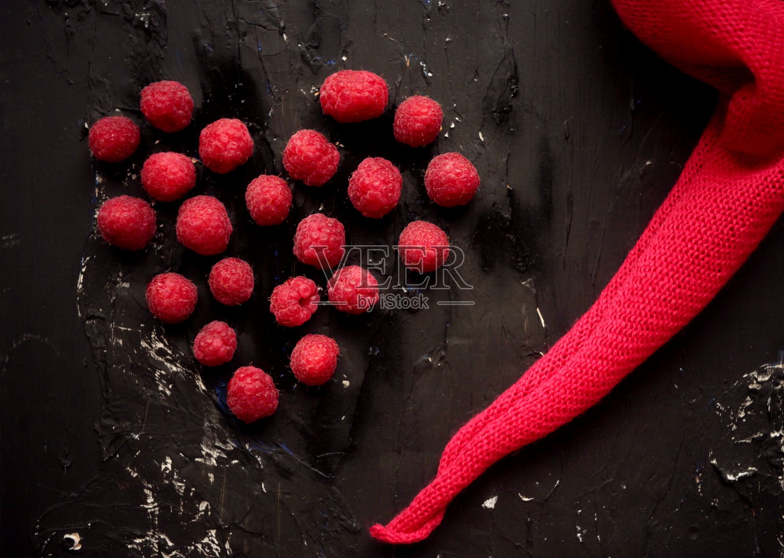 新鲜的覆盆子和粉红色的餐巾在黑色的背景。红心-情人节概念,爱情和友谊的红色颜色。美味的水果和维生素照片摄影图片