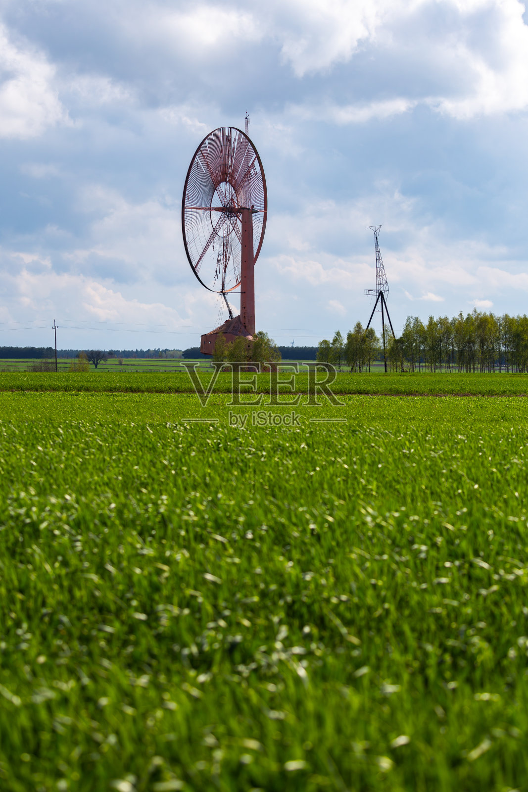 一个古老的、封闭的风电场孤零零地矗立在田野里。物体与天空与微小的云。照片摄影图片