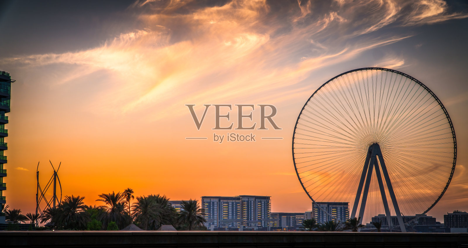 蓝水岛日落:在建的迪拜之眼摩天轮,从码头海滩拍摄,适合日落、旅行和度假照片摄影图片