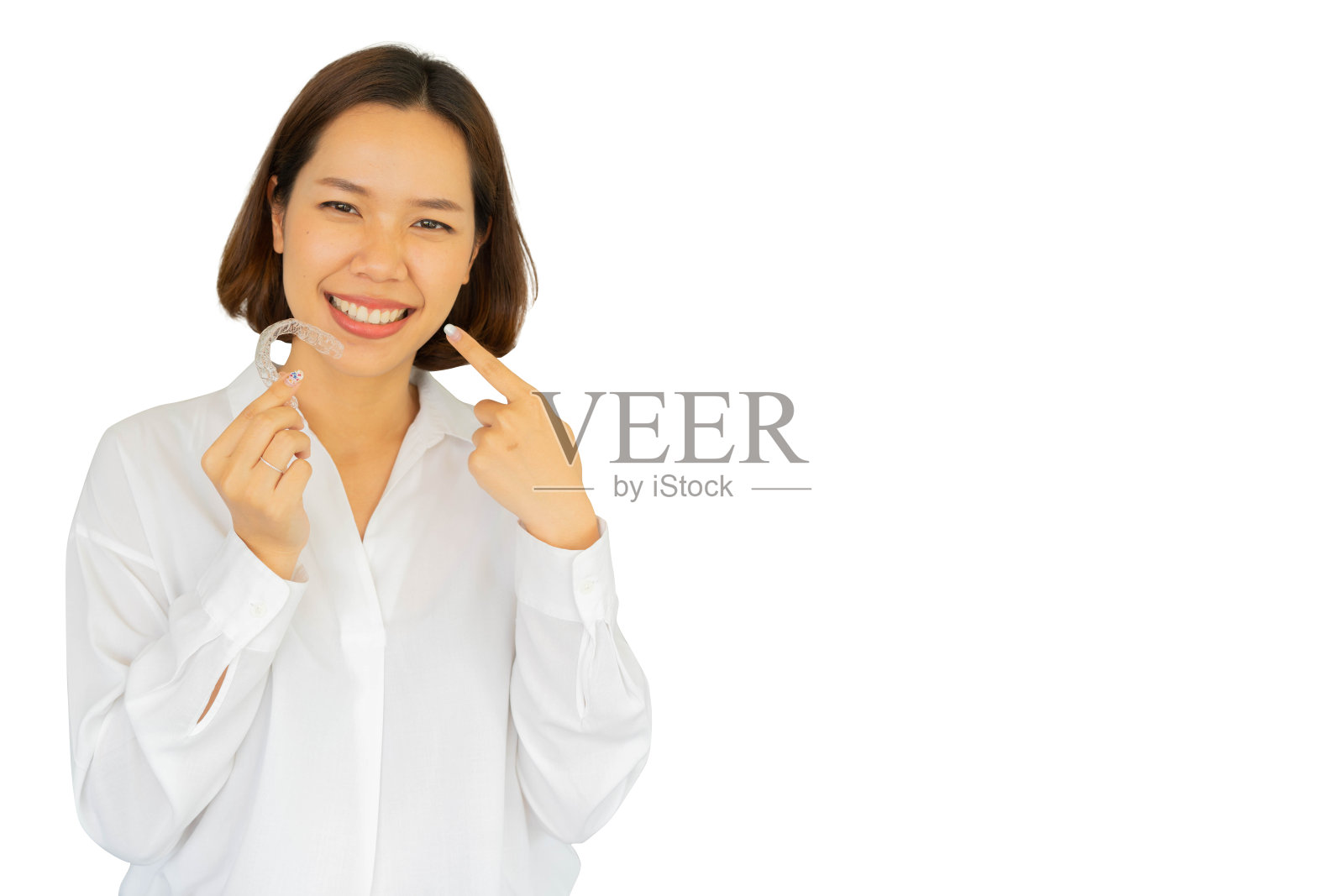 近距离的年轻亚洲美丽的女人微笑与牙齿对准固位器工具(看不见)孤立在白色背景美丽的牙齿治疗课程的概念照片摄影图片