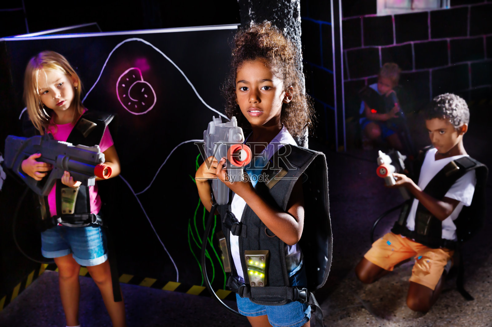 非洲十多岁的女孩用激光枪在黑暗的激光标签上照片摄影图片