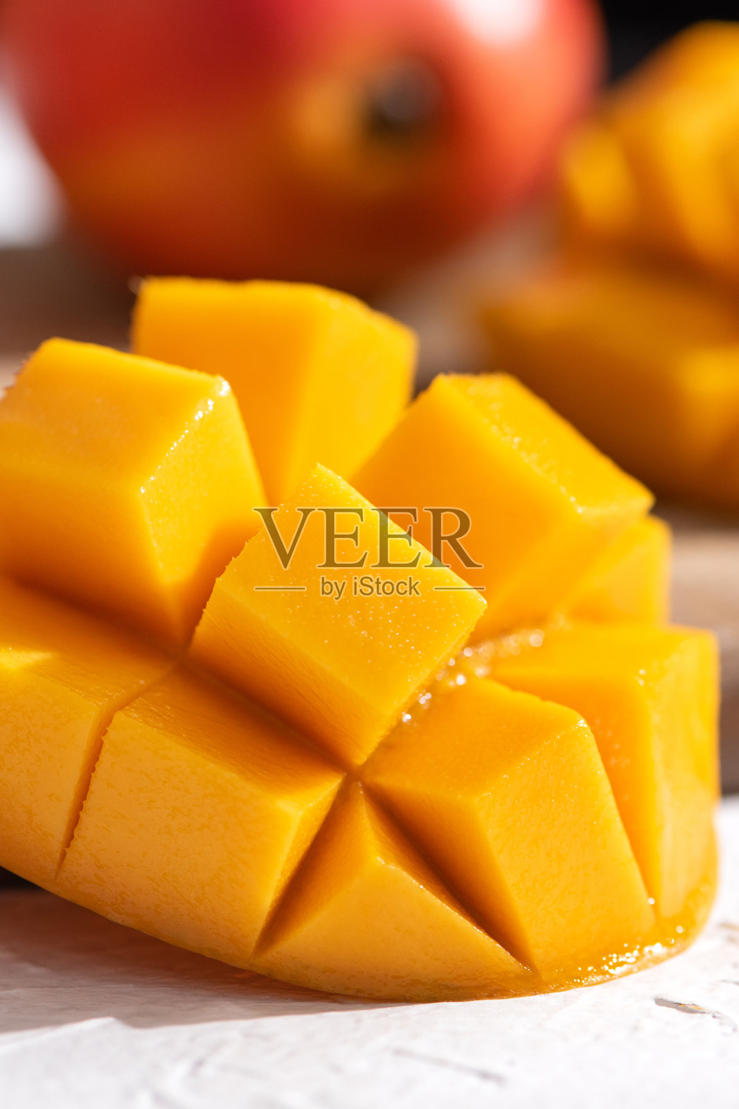 将新鲜的芒果切成小块,放在带有叶子的白色盘子里。照片摄影图片