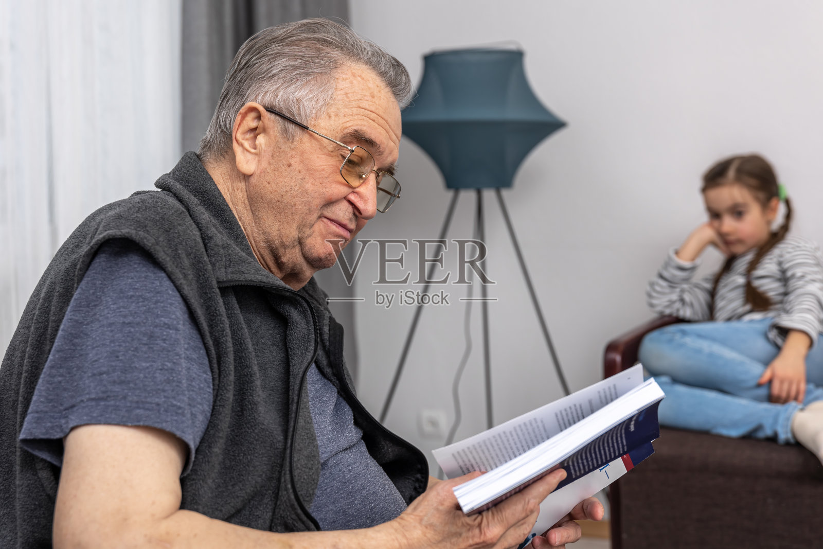 爷爷正在给他的小孙女读书。照片摄影图片
