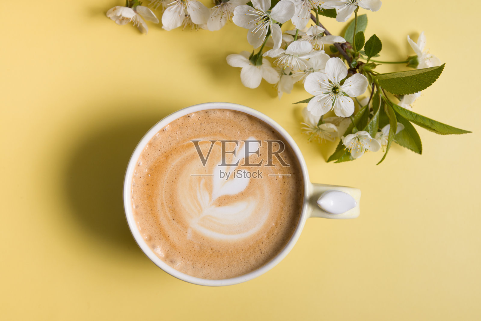 俯视图卡布奇诺在一个美丽的杯子和盛开的樱桃枝照片摄影图片