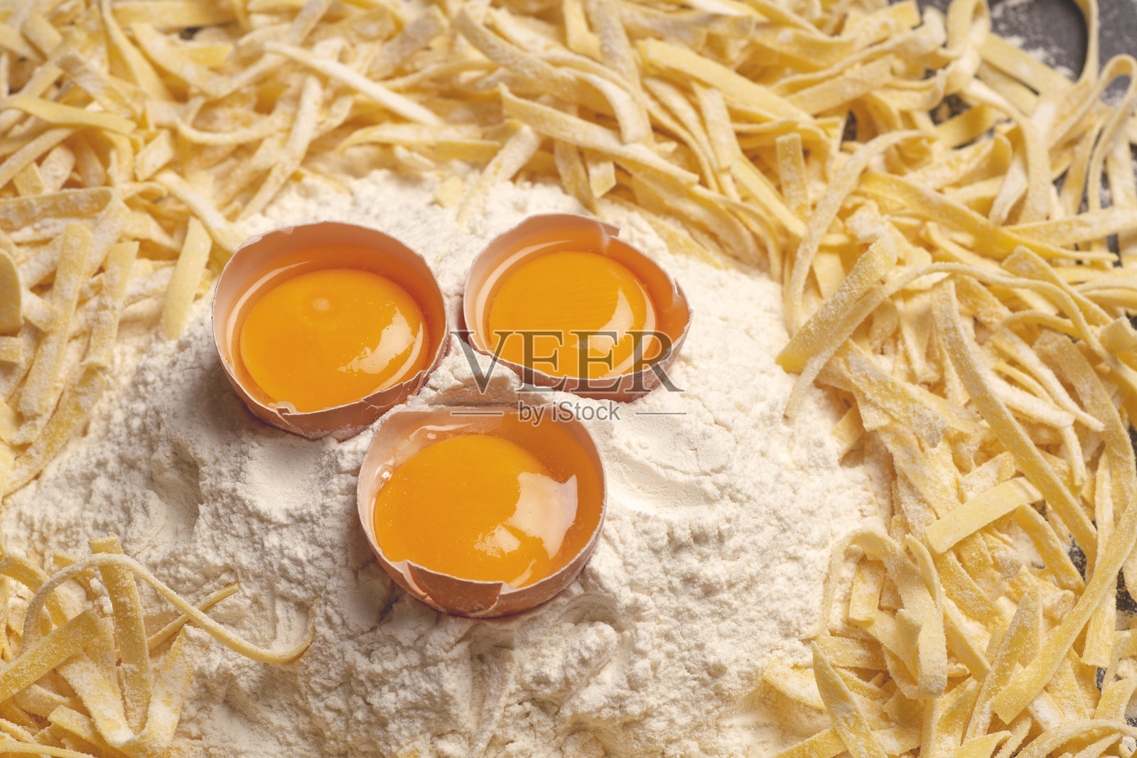 新鲜面食背景。家庭厨房自制的意大利面,用新鲜的鸡蛋和面粉在木背景上做。意大利食物和烹饪的概念照片摄影图片