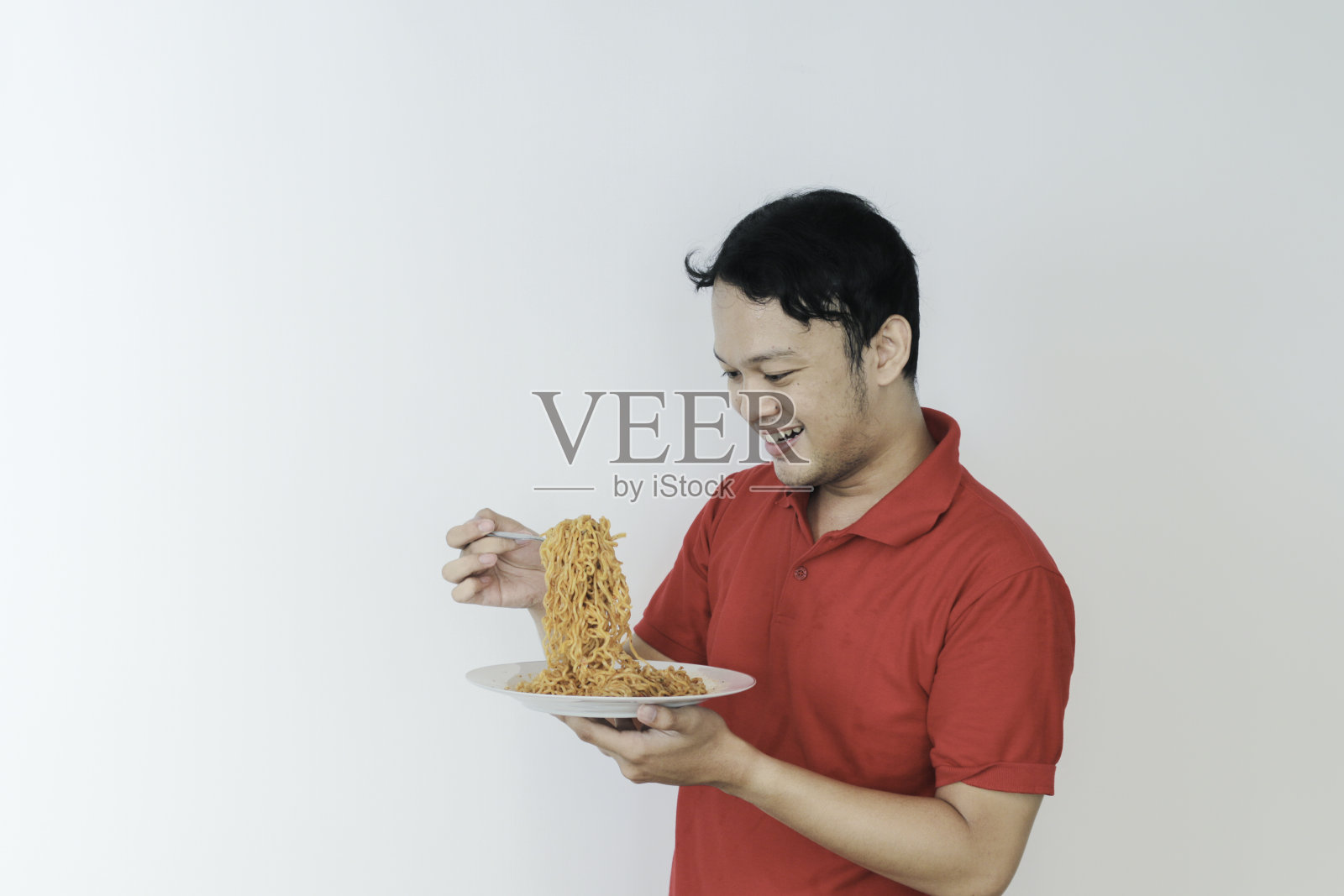 快乐的年轻亚洲男子享受面条肖像。吃午饭的概念。照片摄影图片