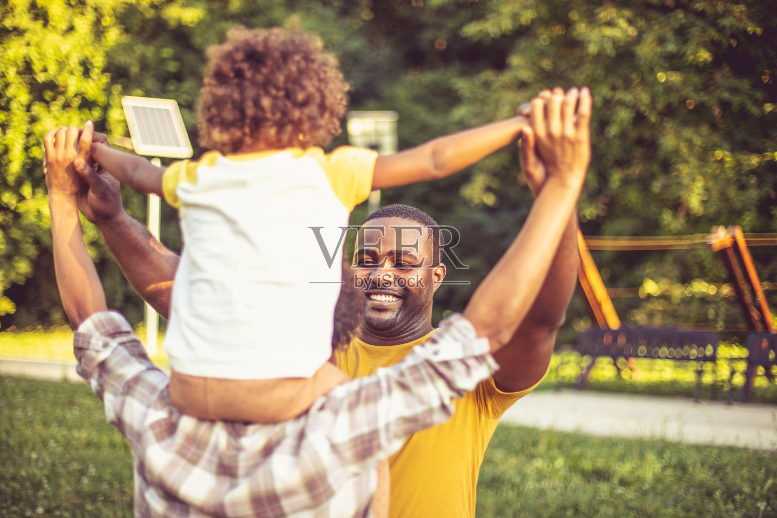 快乐的黑人父母和他们的女儿在公园玩得开心。照片摄影图片