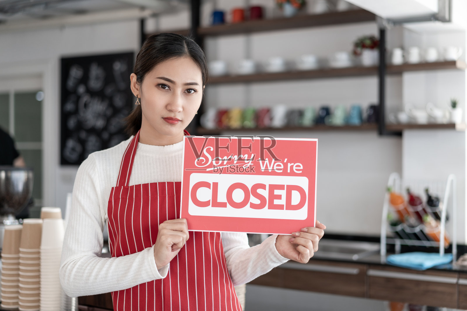 女服务员的肖像站在她的咖啡店门口,展示关闭的招牌照片摄影图片