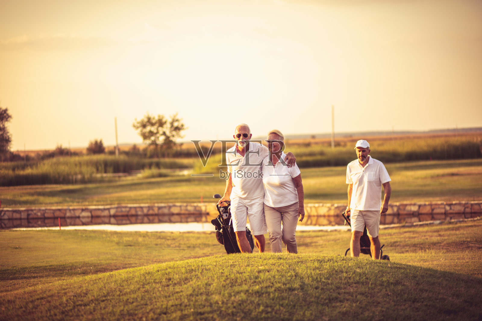 三名老年高尔夫球手。关注男人和女人。快乐的高尔夫球手。照片摄影图片