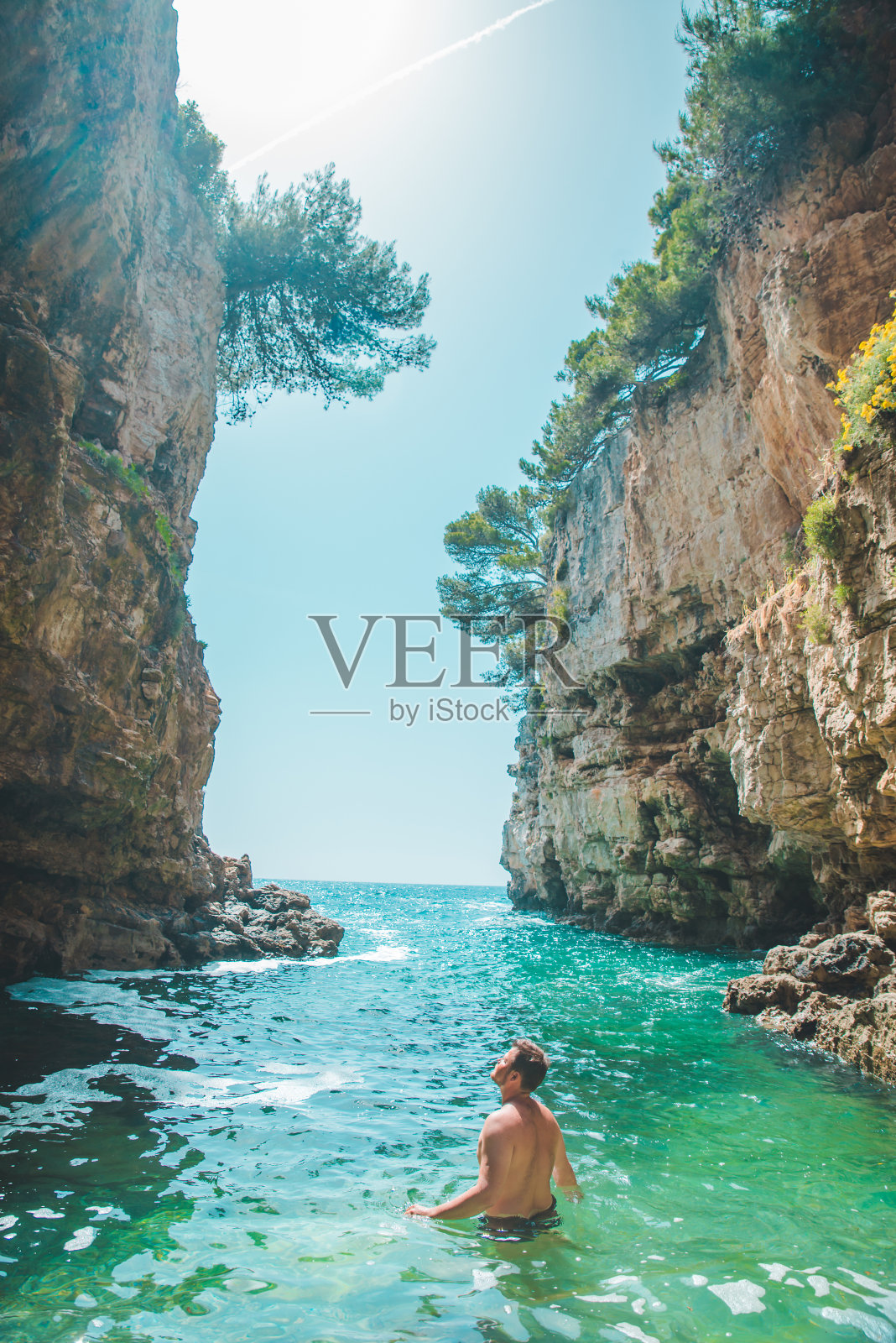 一个年轻人在悬崖之间的海湾里游泳照片摄影图片