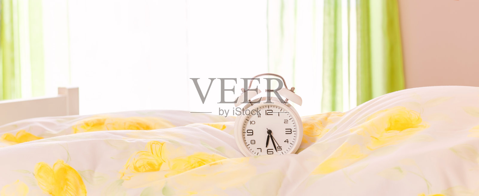 床上的钟。闹钟放在羽绒被上,枕头上。广告的概念照片摄影图片