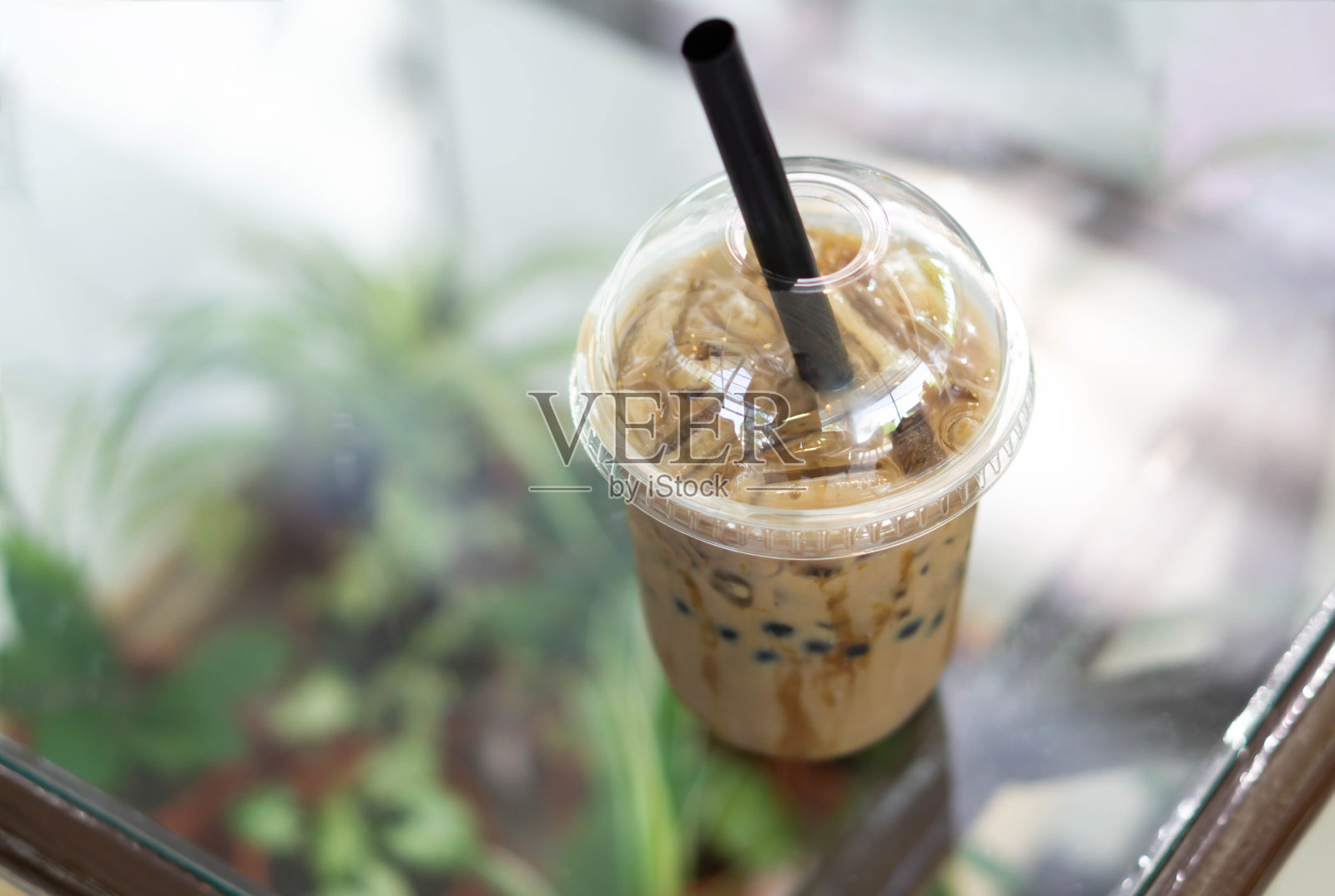 特写冰咖啡在木桌上,以自然为背景照片摄影图片