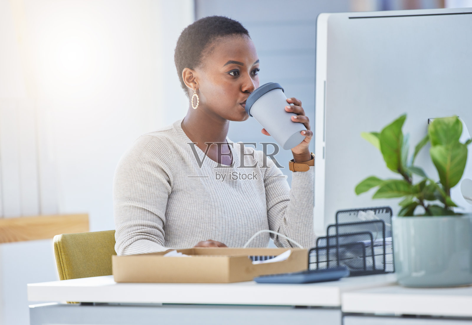 一张年轻女商人坐在办公桌前喝咖啡的照片照片摄影图片