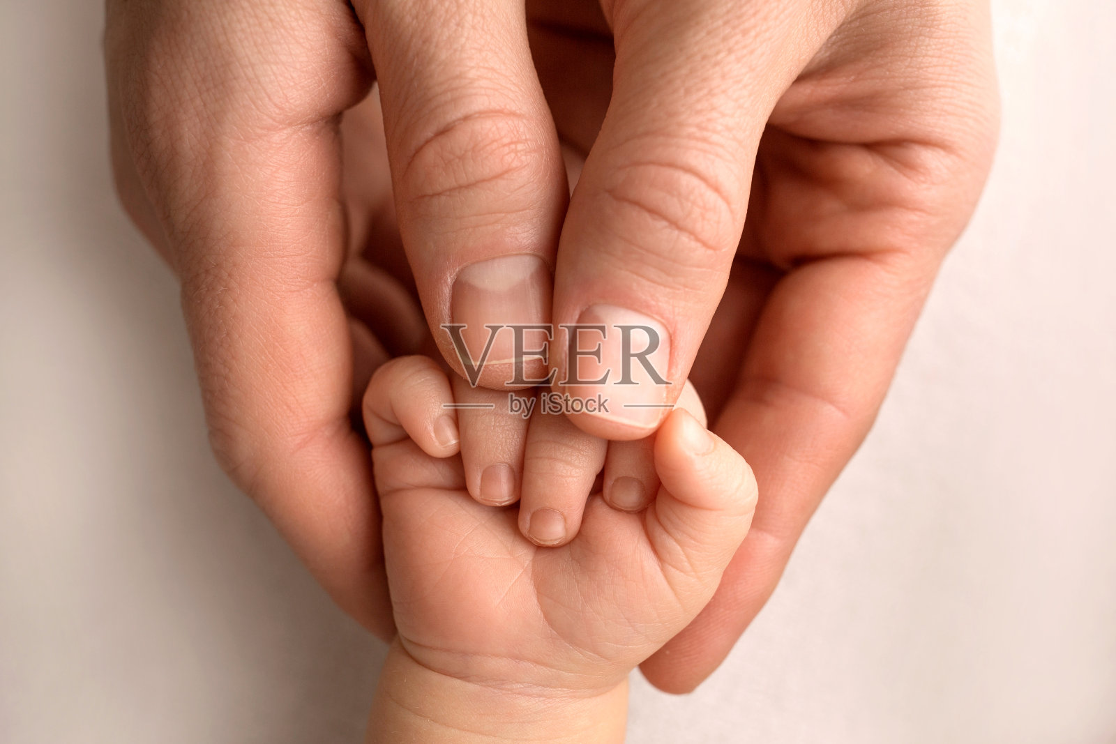 一个新生儿抓住爸爸妈妈的手指。靠近父母和婴儿的手。一个孩子信任她,紧紧地抱着她照片摄影图片