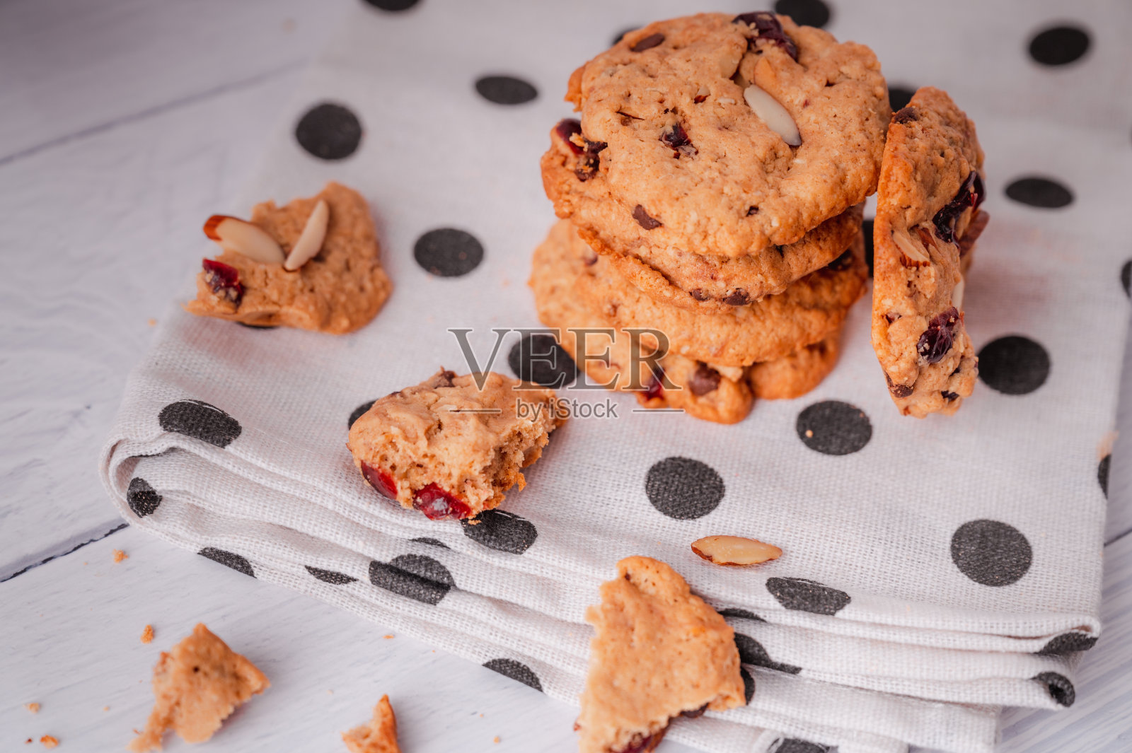 白色的盘子里放着一堆堆美味的巧克力曲奇,还有一个奶瓶。木质桌子上放着配有白色亚麻餐巾的糕点用具。放在白盘子里,再配上一瓶牛奶,真是美味极了。照片摄影图片