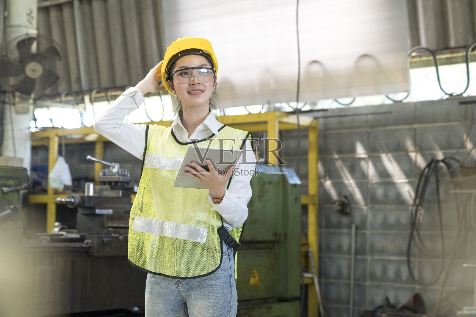 一名女技术员正在一家工厂里使用平板电脑。生产工人在工作中使用平板电脑。照片摄影图片