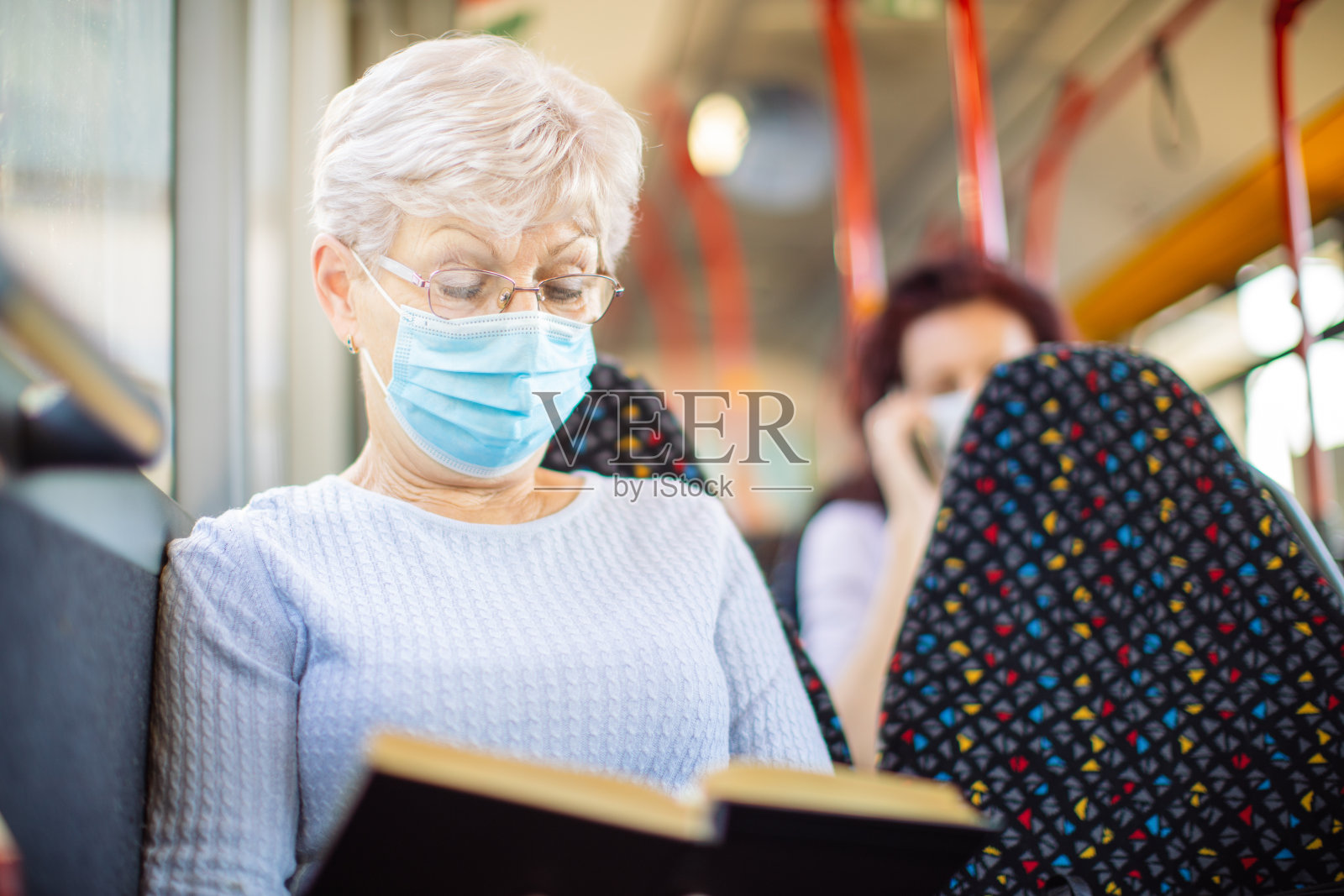 老妇人在公共交通工具上看书照片摄影图片