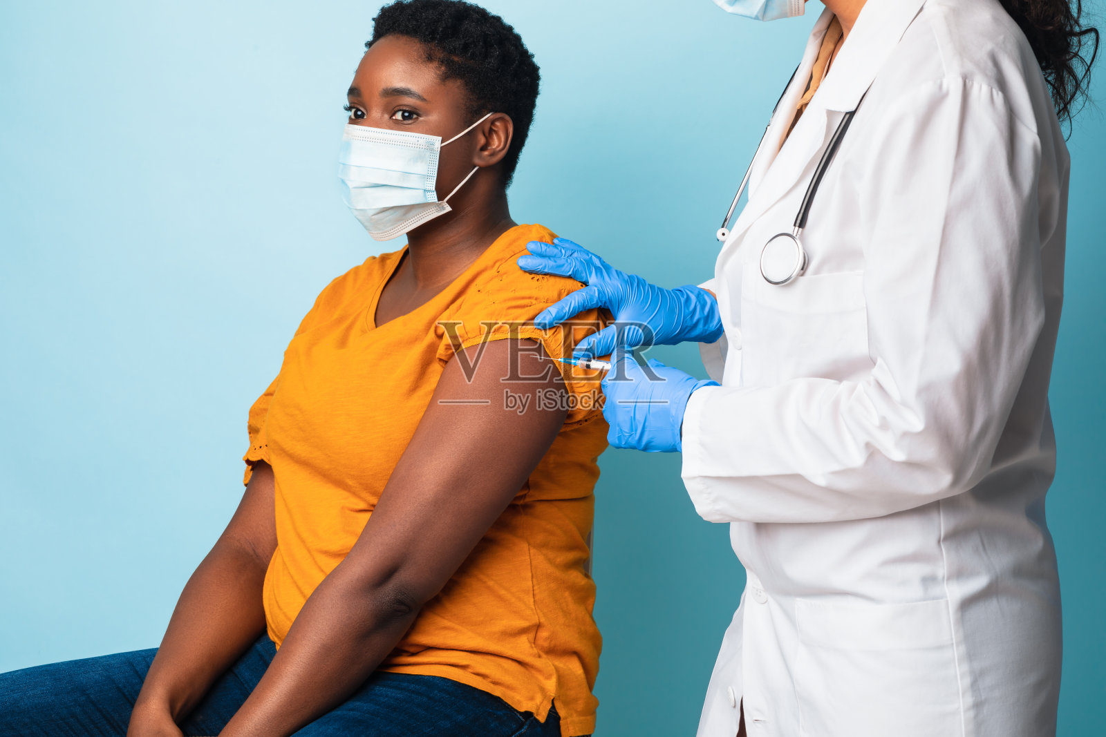 戴口罩的非裔美国女士接受抗病毒疫苗注射,演播室照片摄影图片