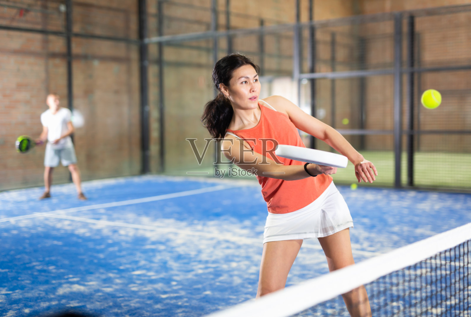 运动的亚洲妇女在室内球场打球拍照片摄影图片