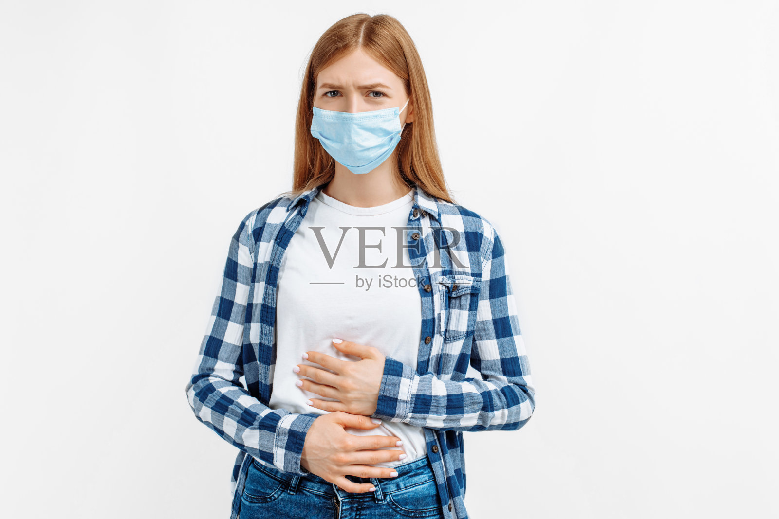 年轻女子戴着保护面罩,双手捂着肚子,肚子痛,背景是白色照片摄影图片