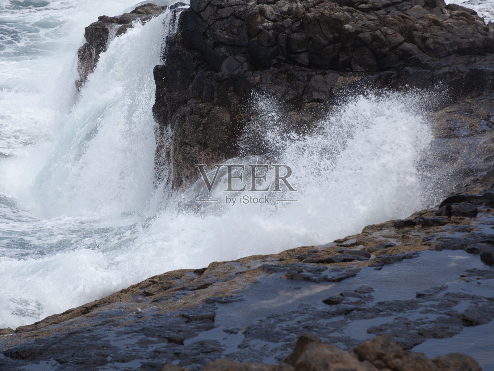 在海里劈波斩浪击打岩石照片摄影图片